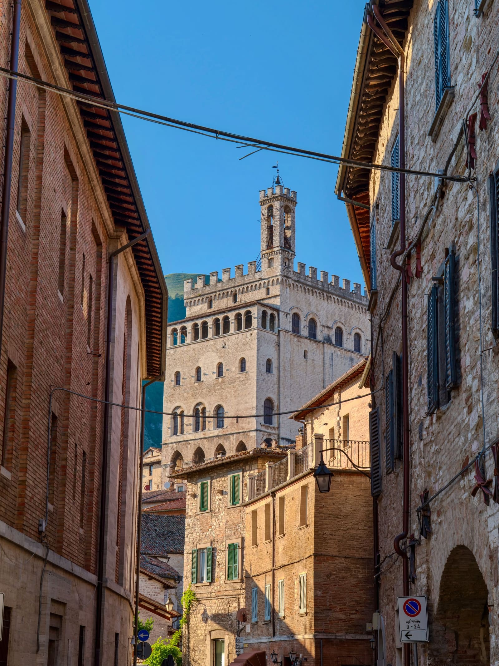 il Palazzo dei Consoli visto dal vicolo che gli sta sotto, con i merli, la torretta campanaria e il monte dietro