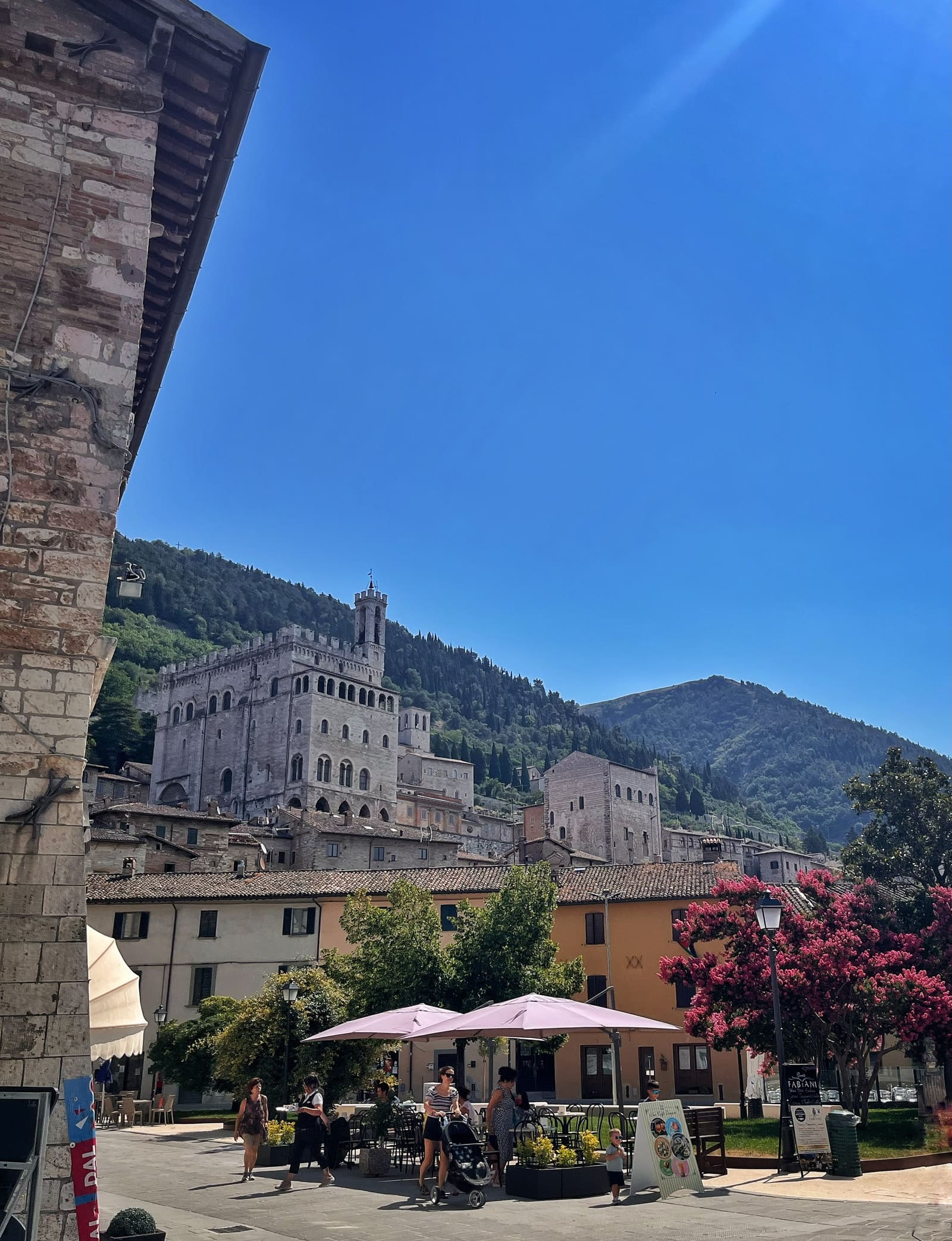 la città vista dalla piazza bassa: il palazzo in alto a sinistra, il monte Ingino dietro e il filo della funivia che lo taglia