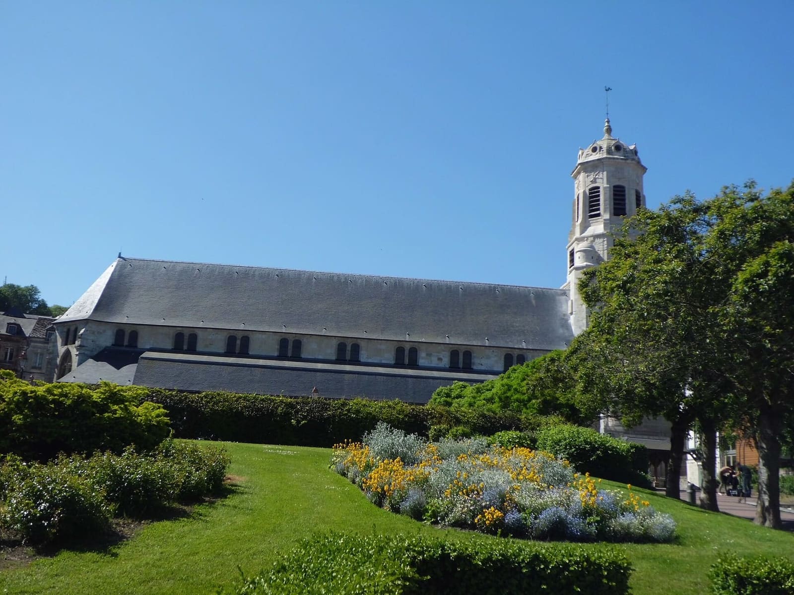 die Église Saint-Léonard mit dem langen Schiff und dem Glockenturm, vom blühenden Garten aus, im Mai