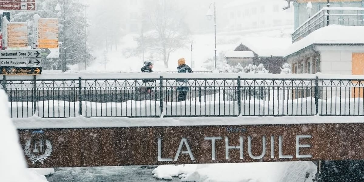 il ponte all'ingresso del paese con la scritta La Thuile in pietra, sotto la nevicata