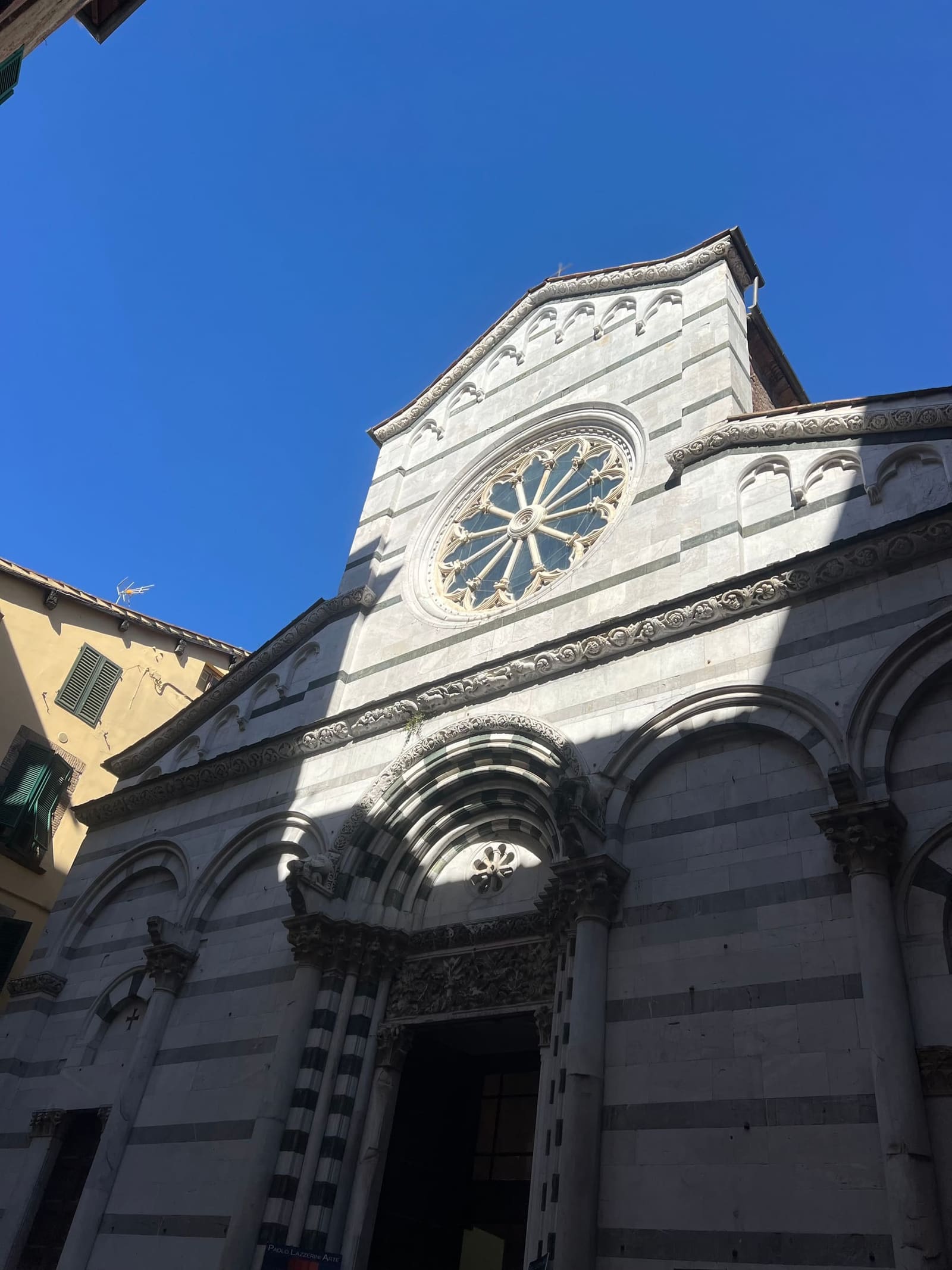 la facciata a fasce di San Cristoforo, con il rosone, su via Fillungo