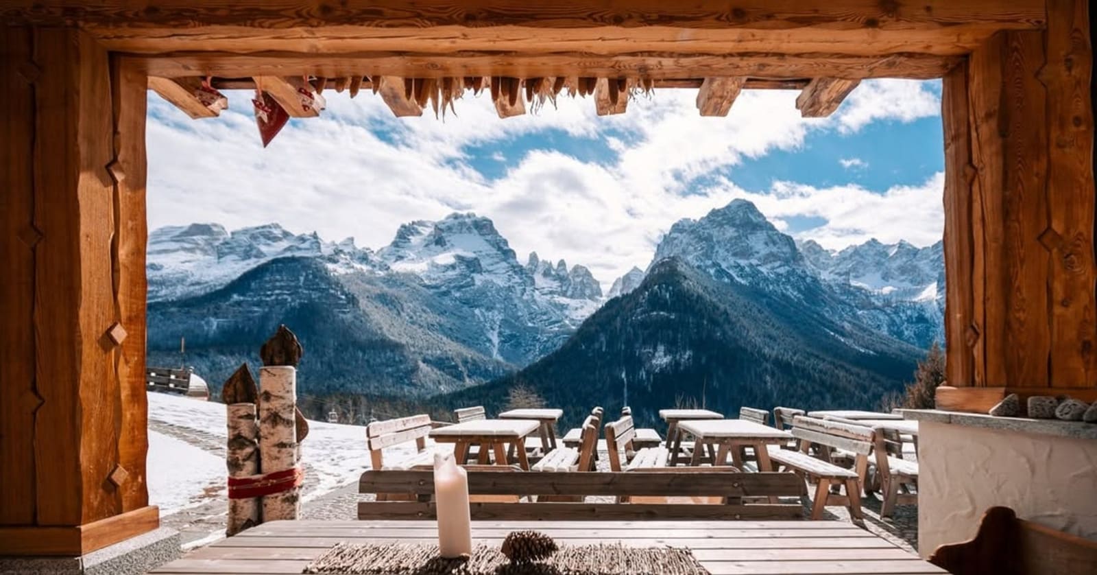 le Dolomiti di Brenta viste dal portico di una malga, con i tavoli di legno sulla neve