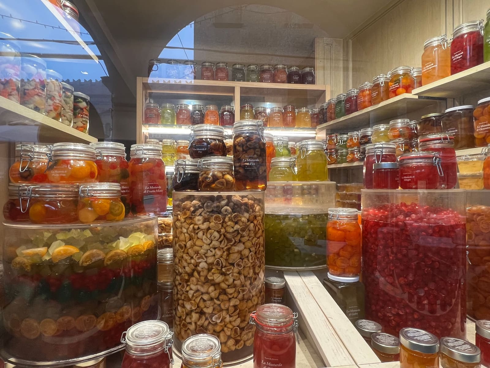 i barattoli di mostarda mantovana nella vetrina di una bottega del centro, di fico, di ciliegia, di cedro e di frutta mista