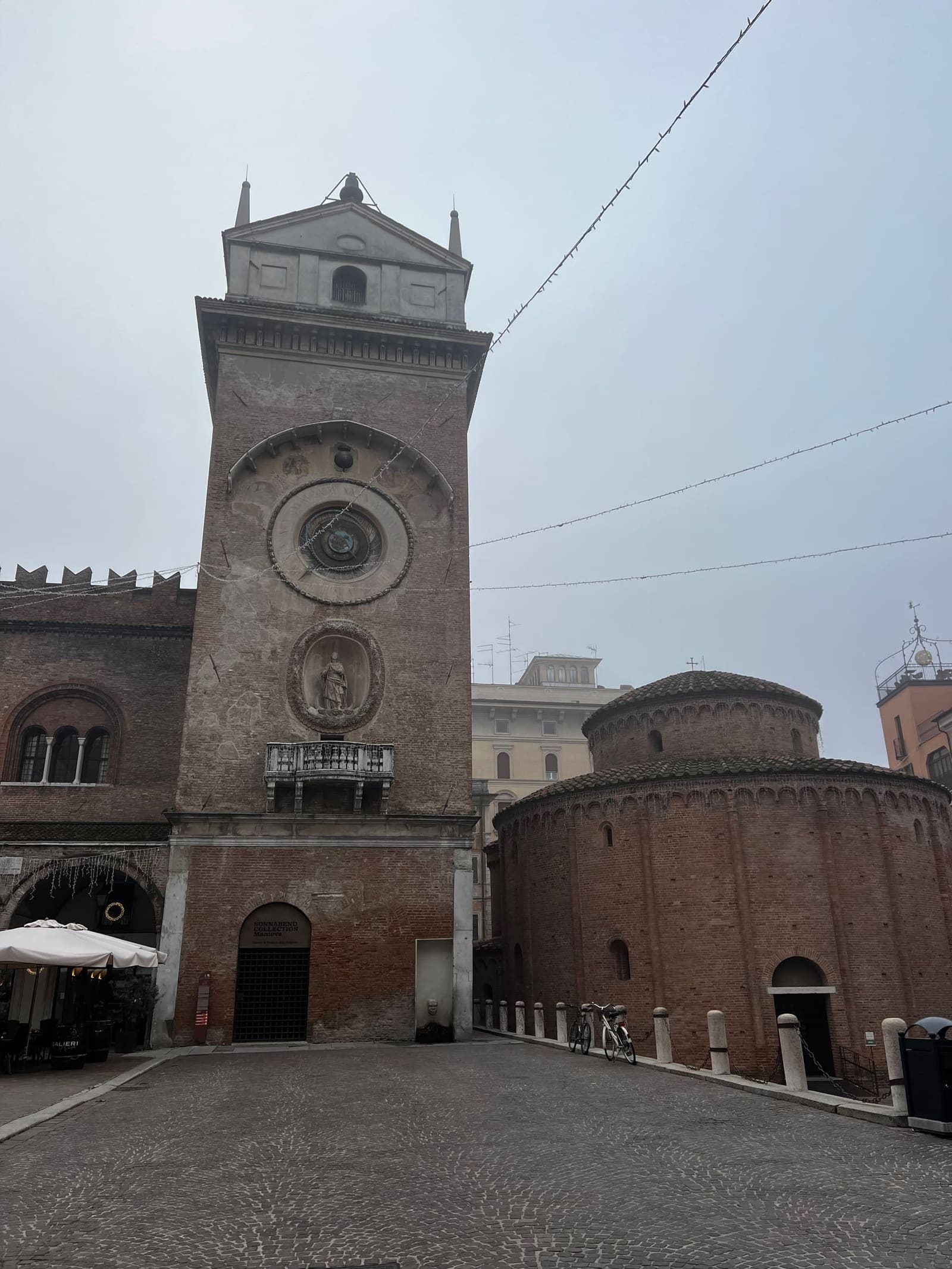 la Torre dell'Orologio e la Rotonda di San Lorenzo in Piazza Erbe, in una mattina di nebbia