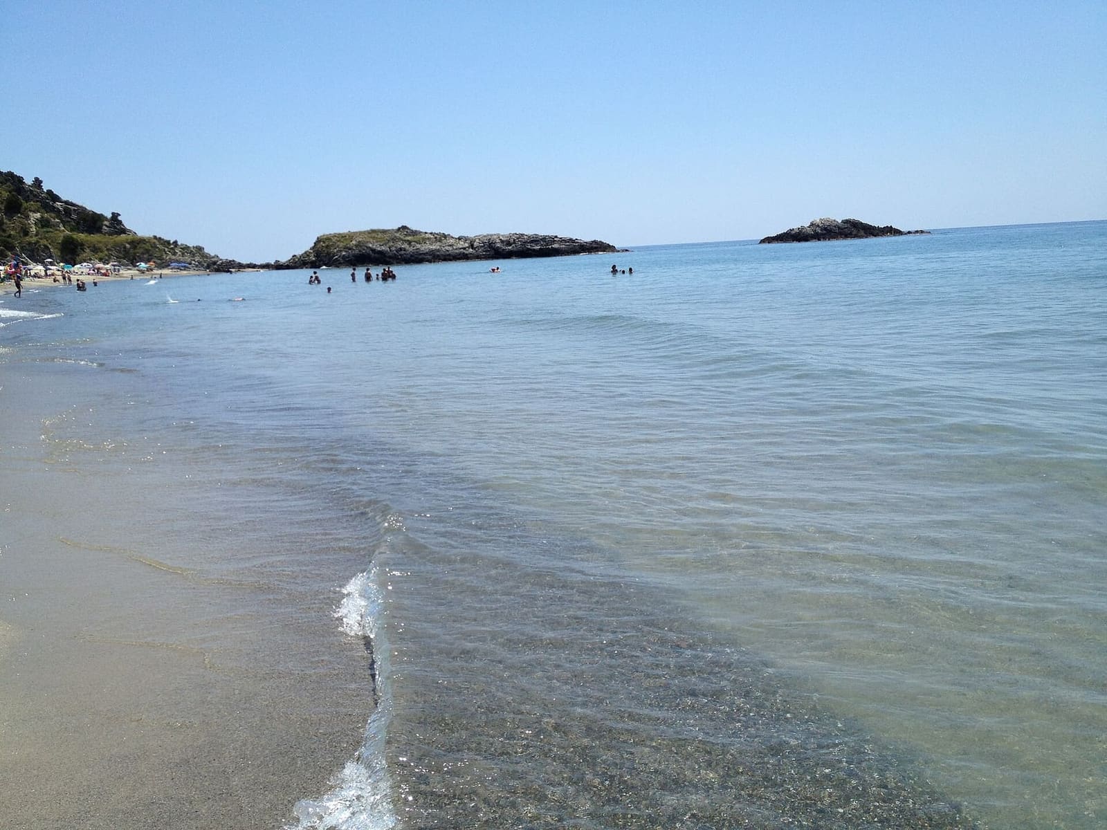 der Strand mit flachem Wasser und den Felsen vor der Küste, im Sommer
