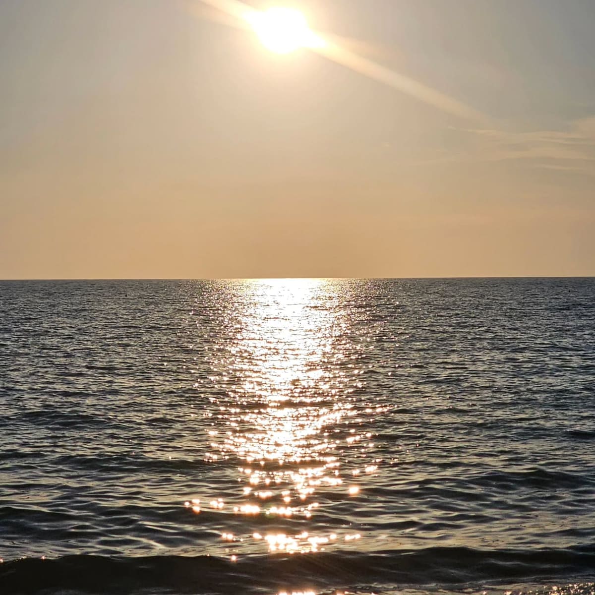 il sole basso sull'acqua e la scia di luce fino alla riva