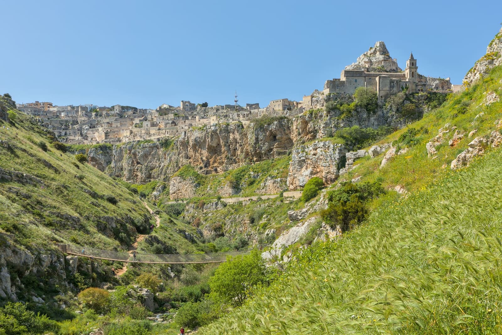 il ponte sospeso del sentiero 406 in fondo alla gravina, con le case dei Sassi sulla rupe in alto