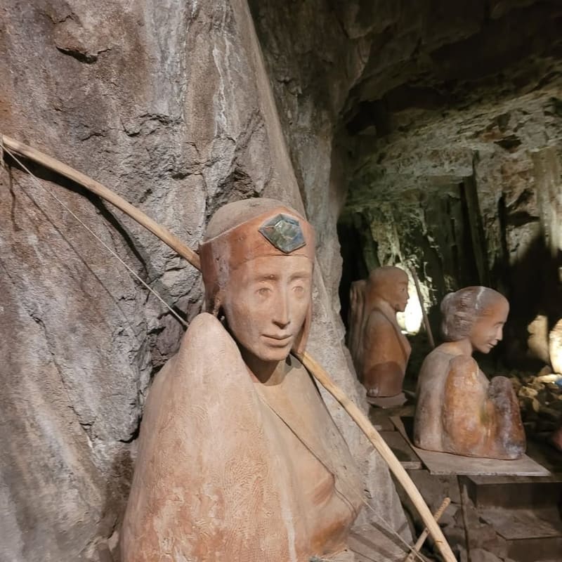 figure scolpite addossate alla parete di roccia, la prima con l'arco appoggiato alla spalla