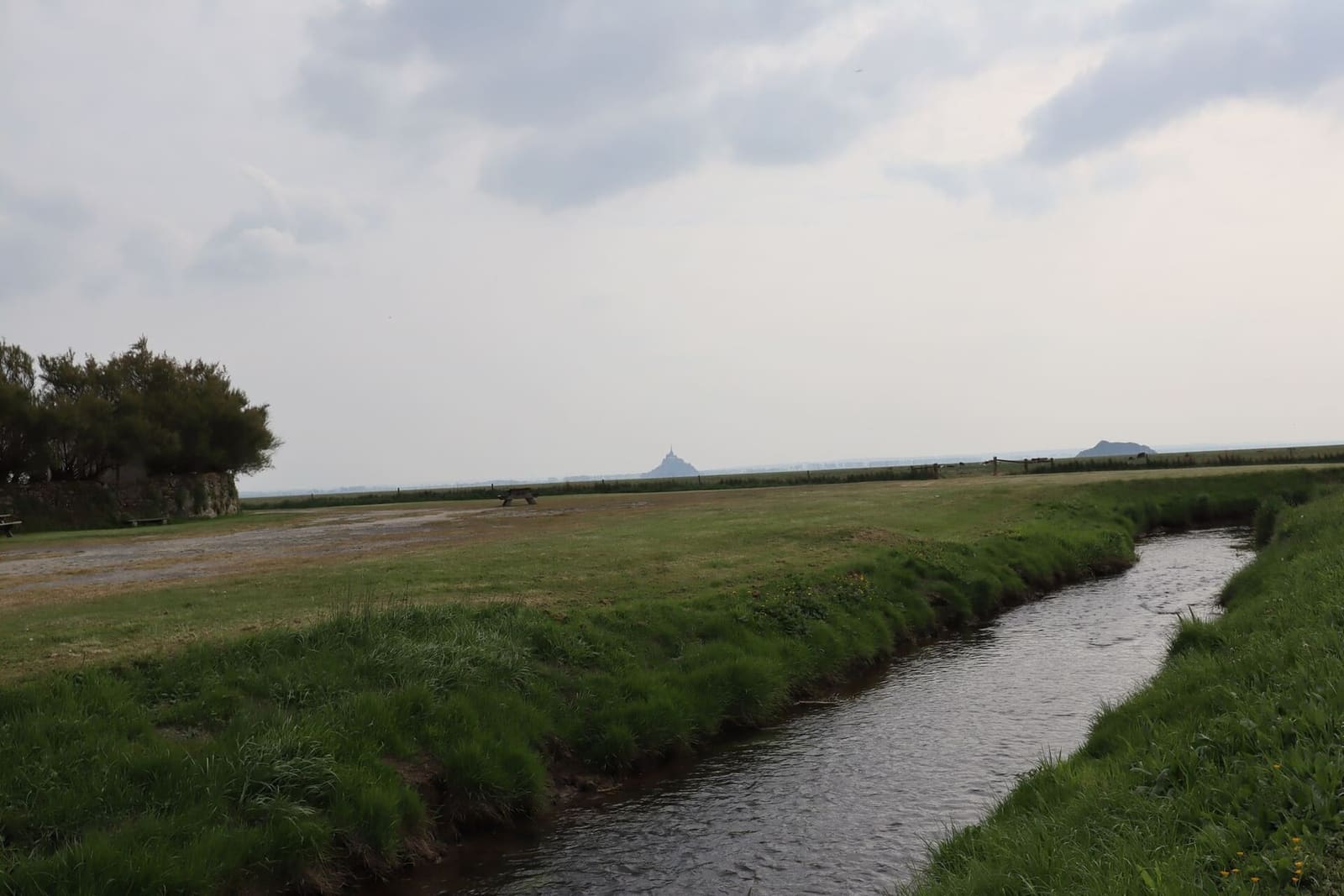 un canale nei prati di Genêts, con il Mont e Tombelaine lontani, all'inizio di maggio