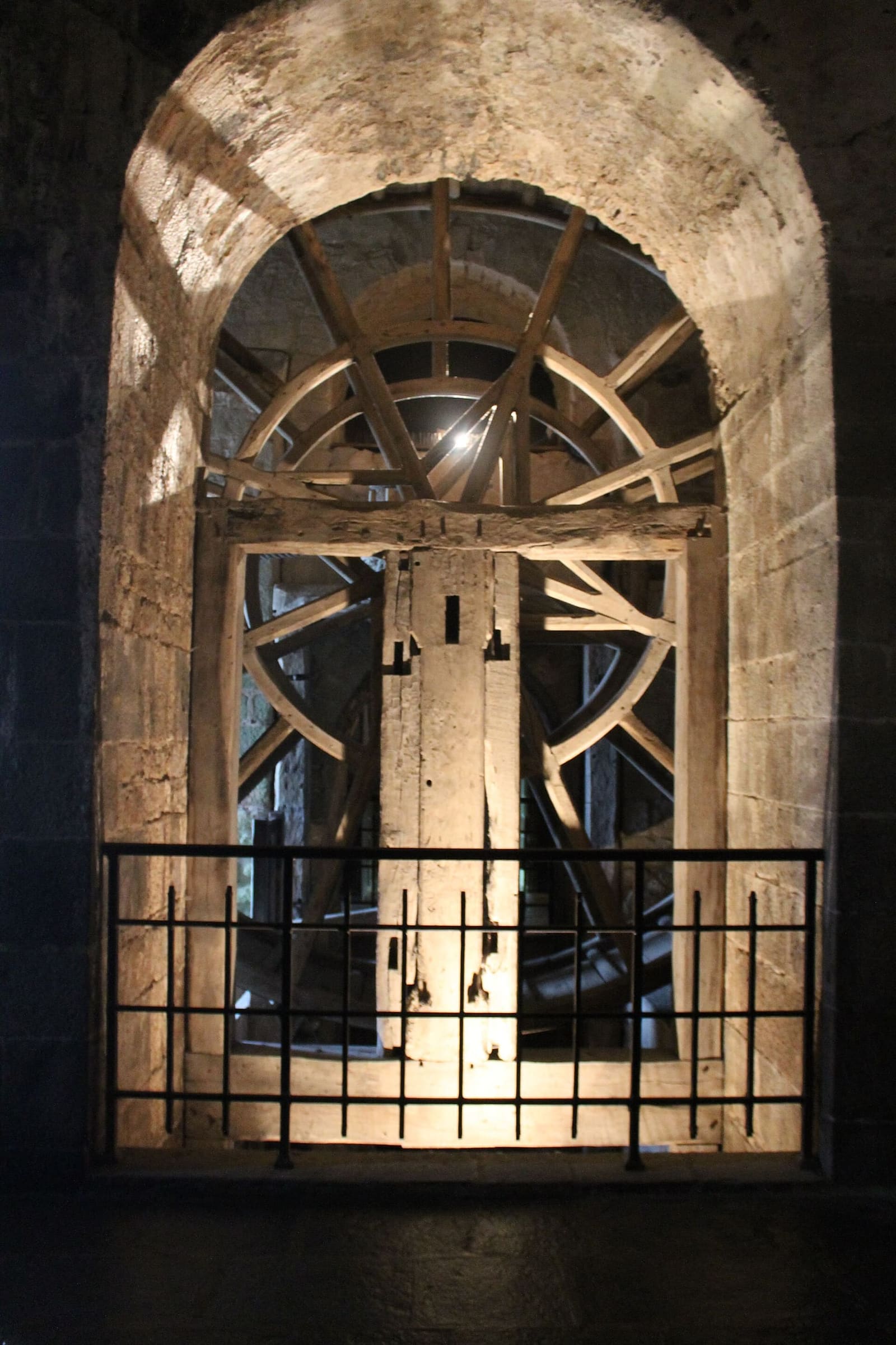 la grande ruota di legno con cui si tiravano su i carichi, illuminata nella sua nicchia