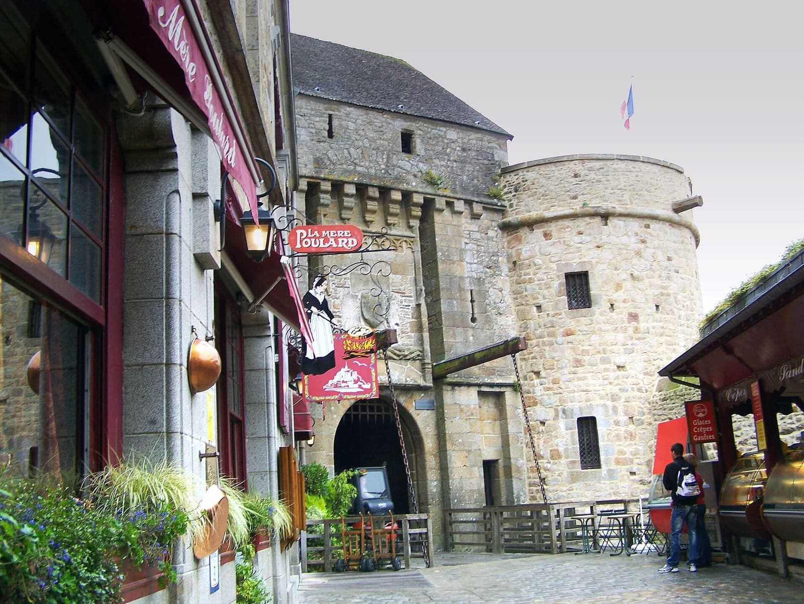 la porte du Roy con le catene del ponte levatoio e la tour du Roy, e a sinistra l'insegna della Mère Poulard