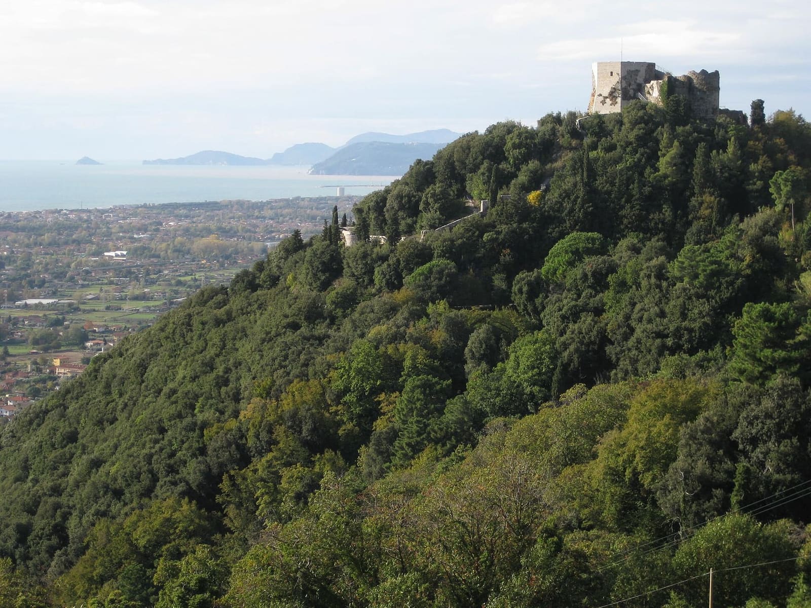 das Castello Aghinolfi auf dem Hügel über der Ebene, mit dem Meer und den Vorgebirgen des Golfs von La Spezia im Hintergrund