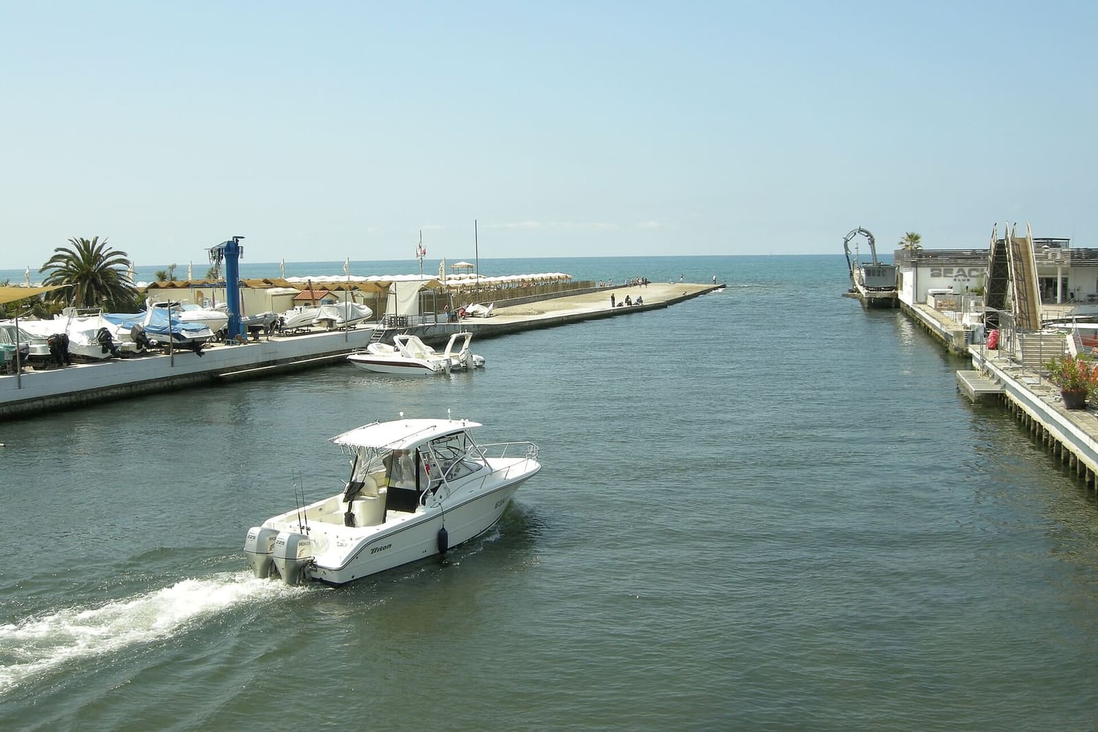 ein Boot fährt aus der Mündung des Versilia in Cinquale, zwischen den Kais des kleinen Hafens