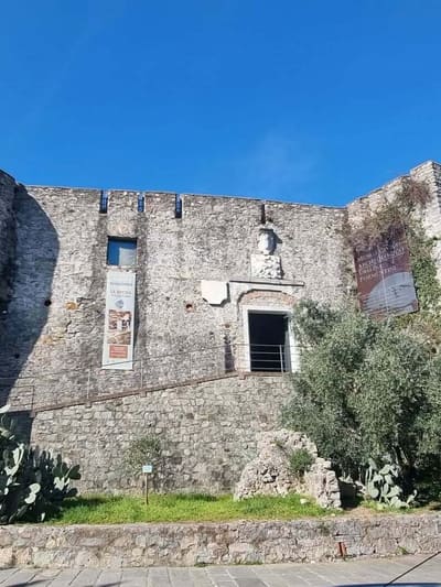il muraglione di pietra del Castello di San Giorgio, con lo striscione del Museo Civico Archeologico Ubaldo Formentini a destra della porta