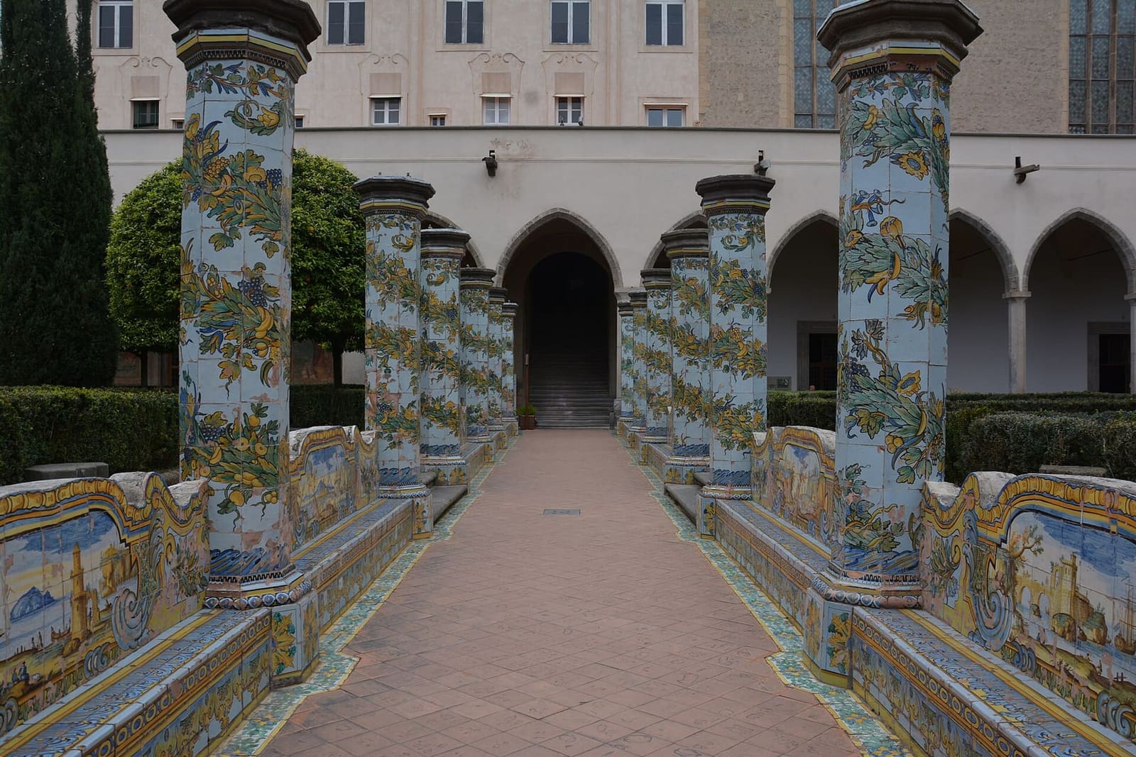 il viale del chiostro di Santa Chiara fra i pilastri rivestiti di maioliche gialle e verdi