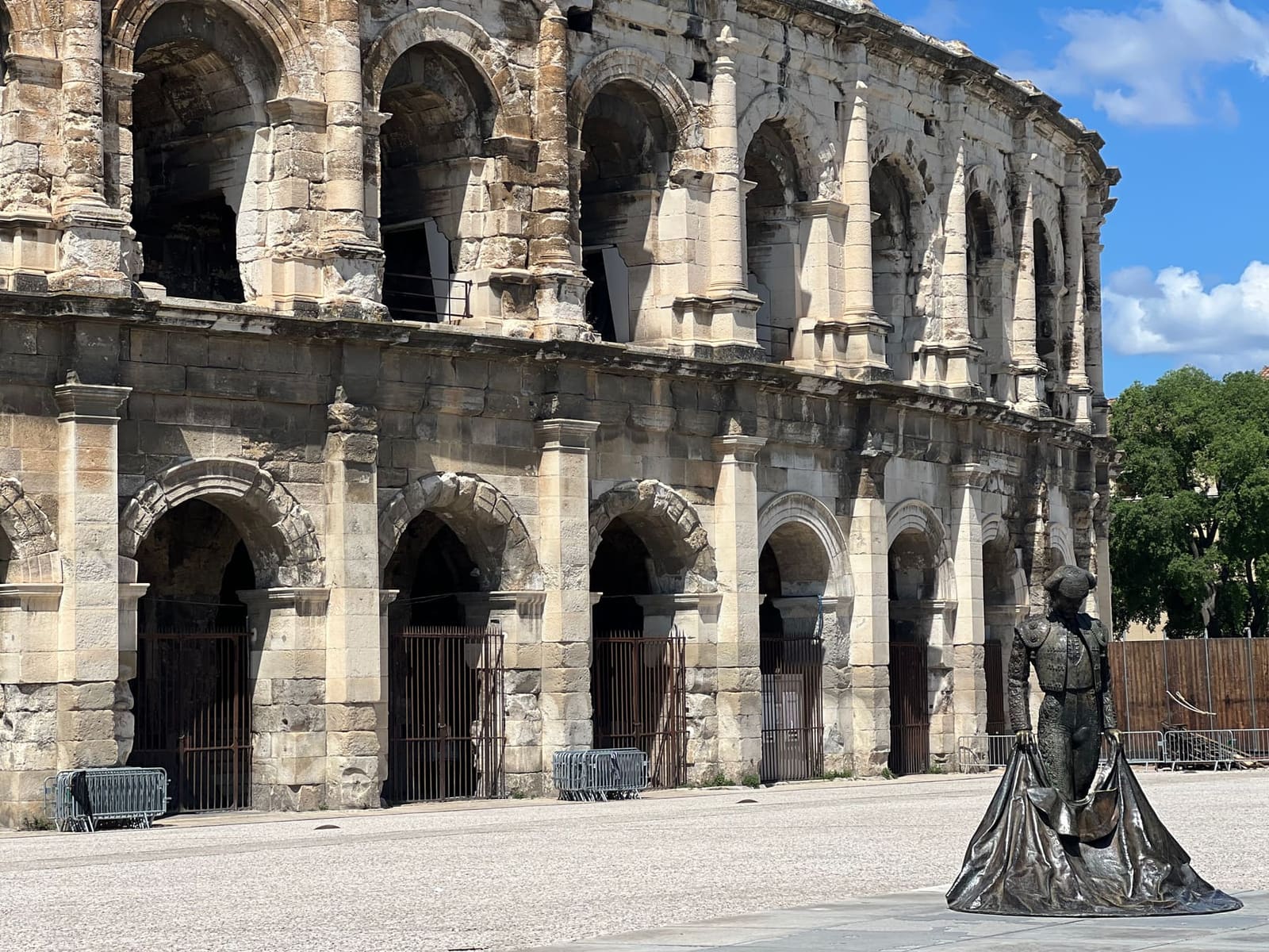le arcate dell'arena e la statua di Nimeño II sulla piazza deserta