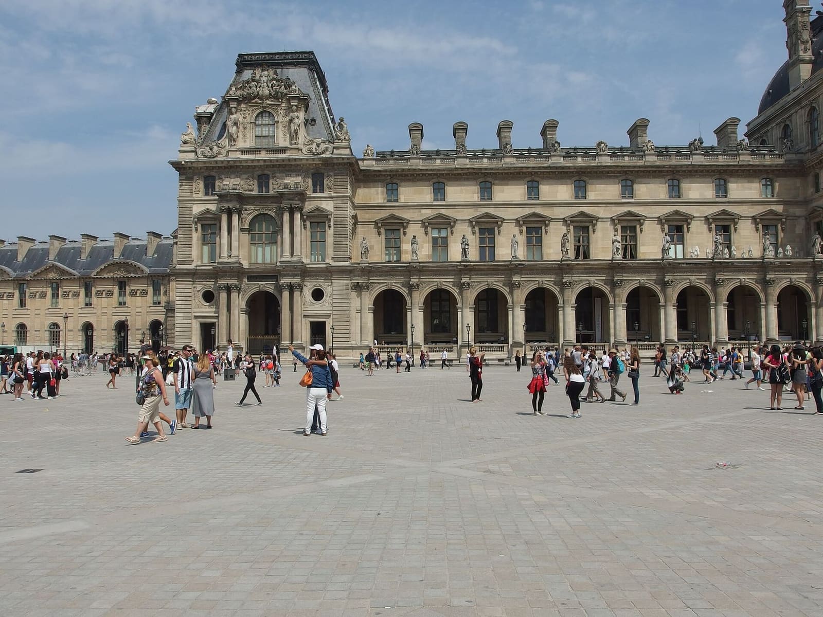 ein Pavillon des Louvre und die Arkaden mit den Statuen an der Fassade, vom Platz vor dem Museum aus