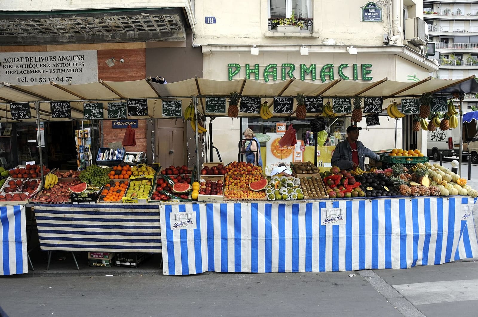 ein Obst- und Gemüsestand unter den gestreiften Markisen des Marché d'Aligre