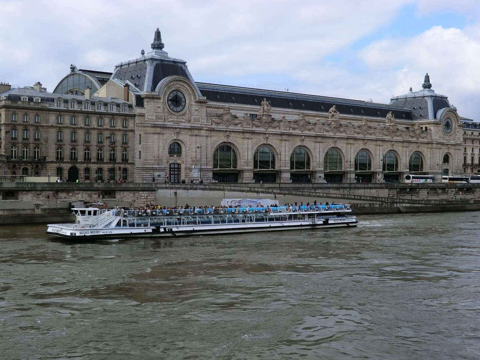 das Musée d'Orsay, der alte Bahnhof, an der Seine mit einem vorbeifahrenden Boot