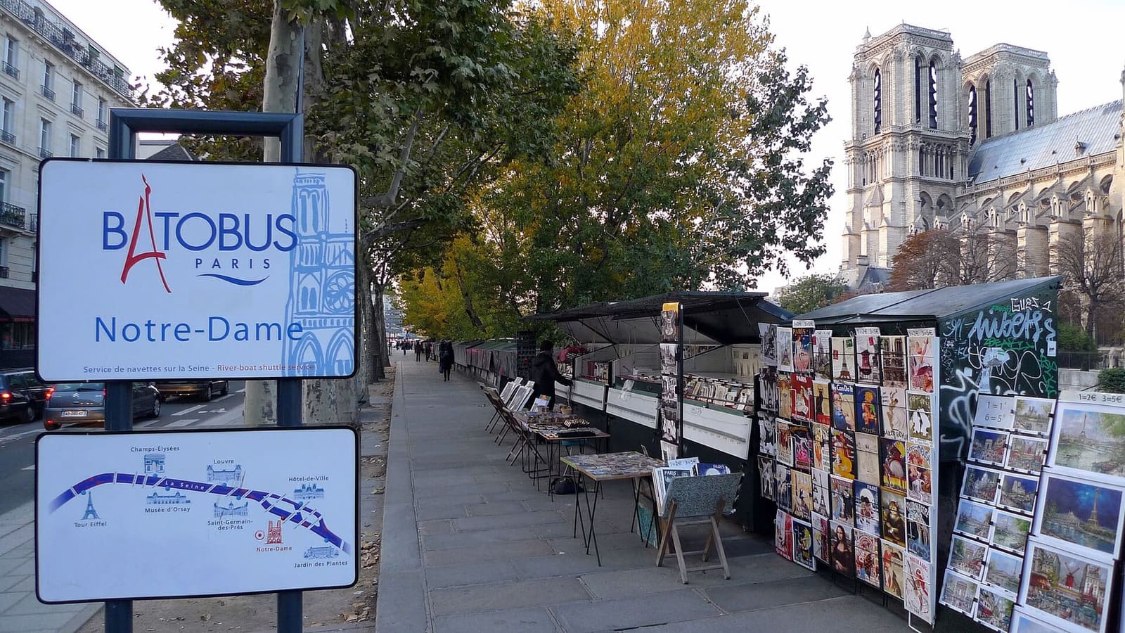 das Schild der Batobus-Haltestelle Notre-Dame am Quai de Montebello, zwischen den Kästen der Bouquinisten