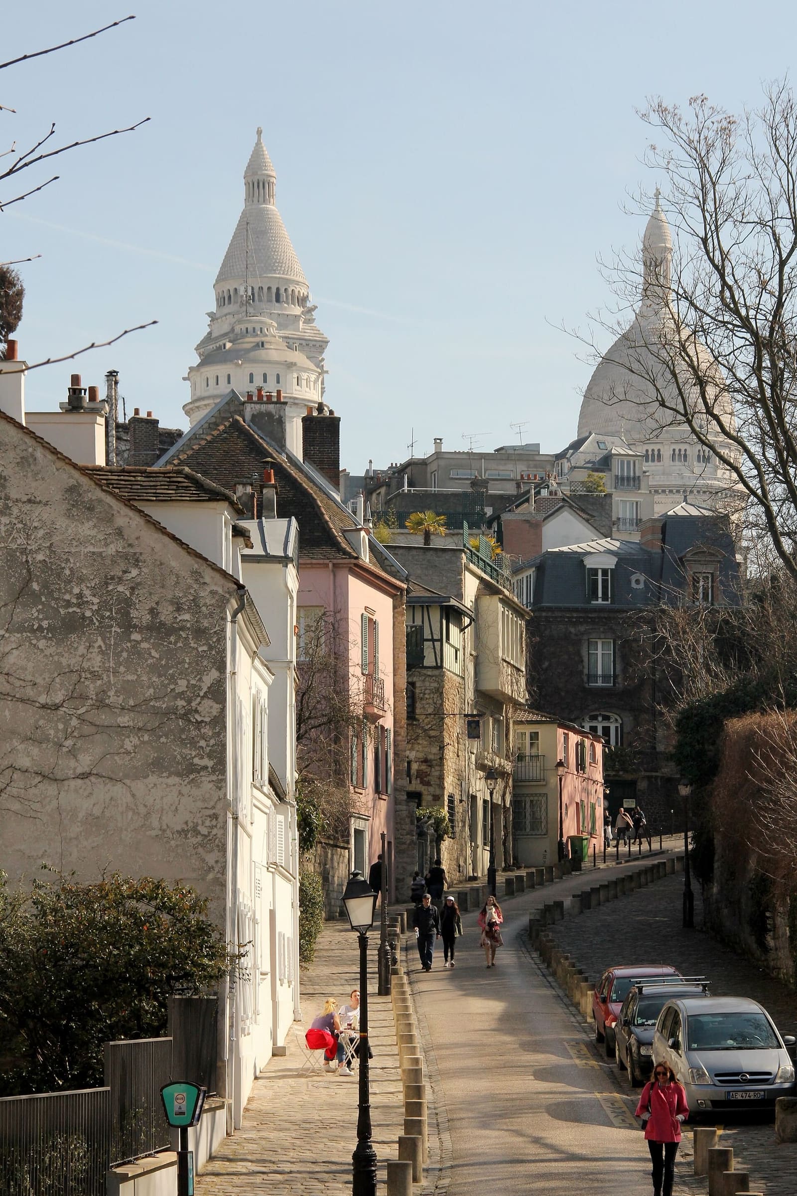 die ansteigende Rue de l'Abreuvoir zwischen den niedrigen Häusern von Montmartre, am Ende die Kuppeln von Sacré-Cœur