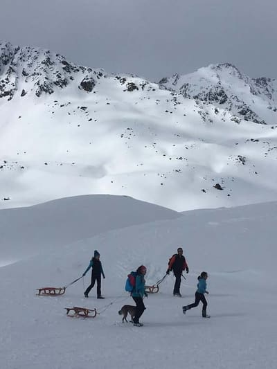 in cammino sull'altopiano con gli slittini di legno al traino, sopra il limite del bosco
