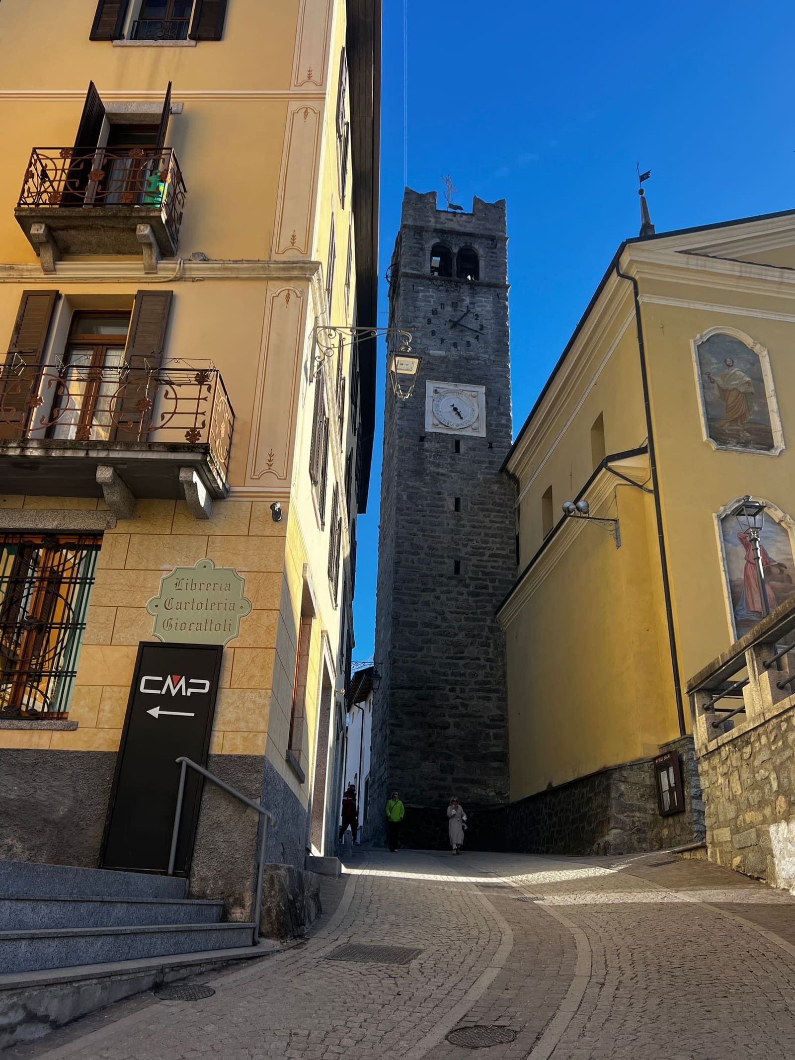 il campanile in pietra con l'orologio e la meridiana, in fondo al vicolo del centro