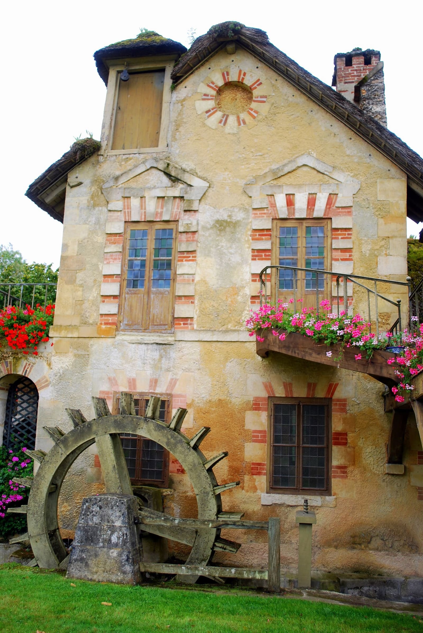 die Mühle im Weiler der Königin mit dem hölzernen Rad und Geranien am Fenster