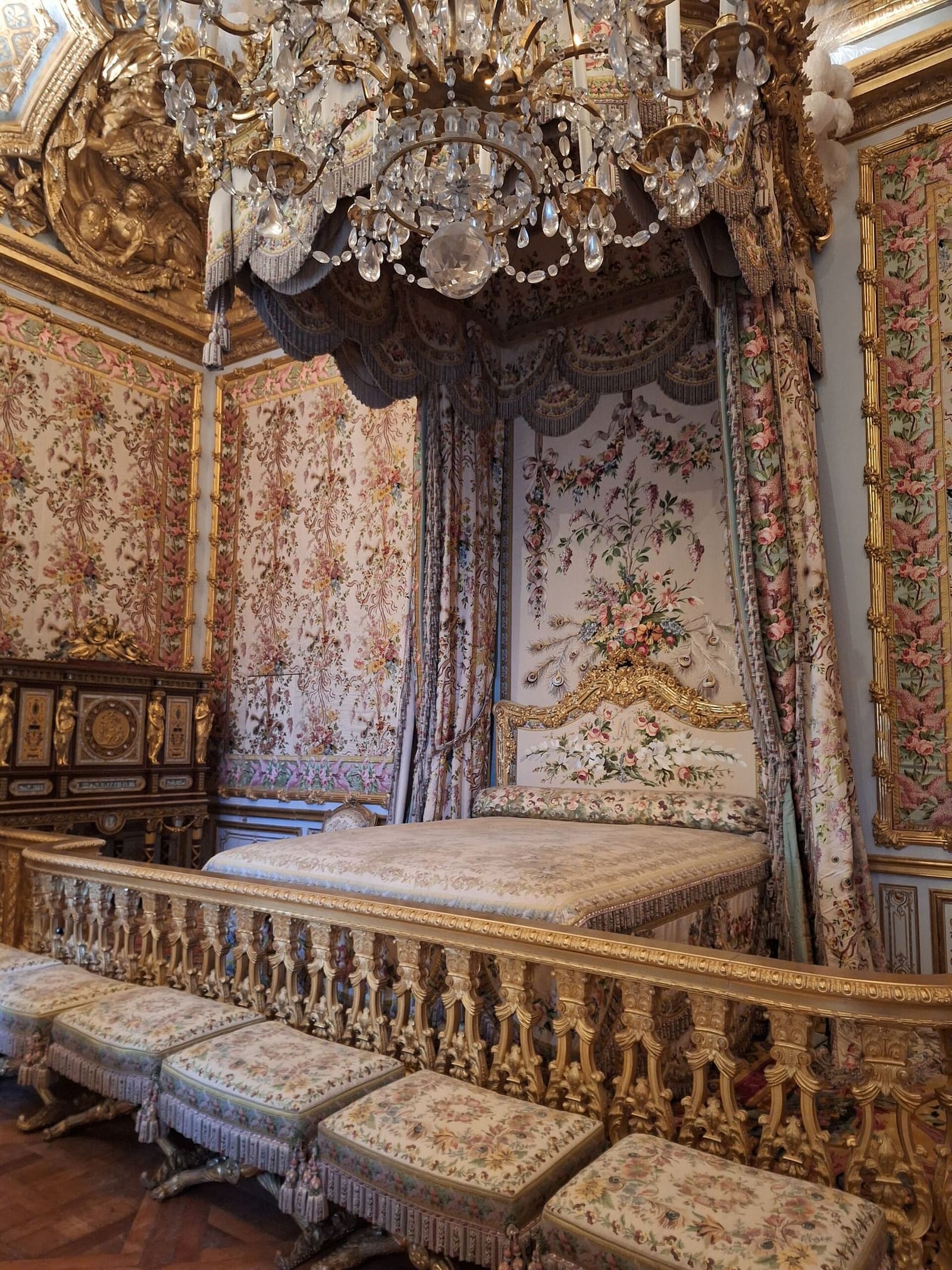 das Himmelbett und die geblümten Stoffe im Schlafzimmer der Königin