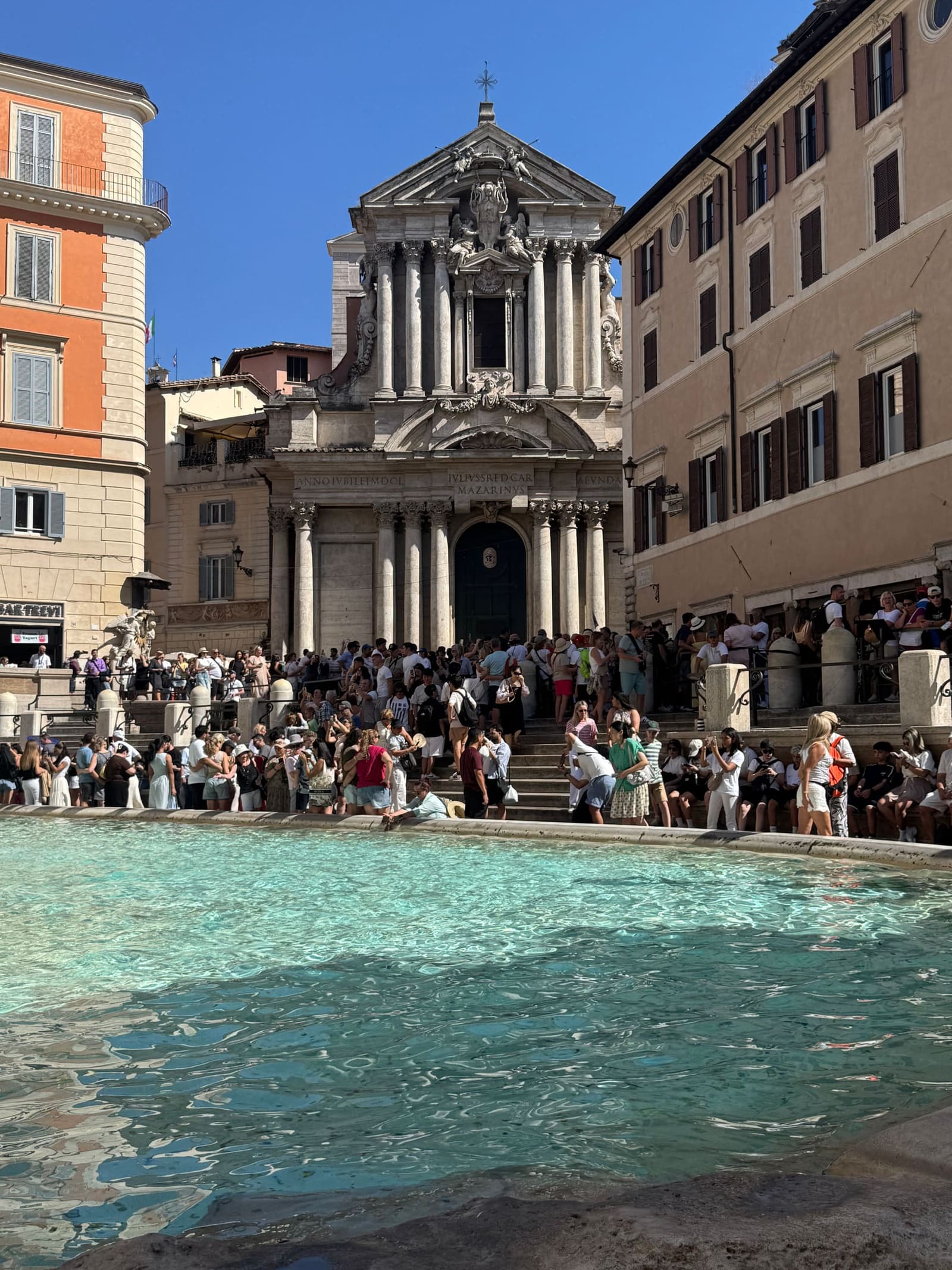 la chiesa dei Santi Vincenzo e Anastasio in faccia alla fontana, con la folla seduta sui gradini che guarda dall'altra parte