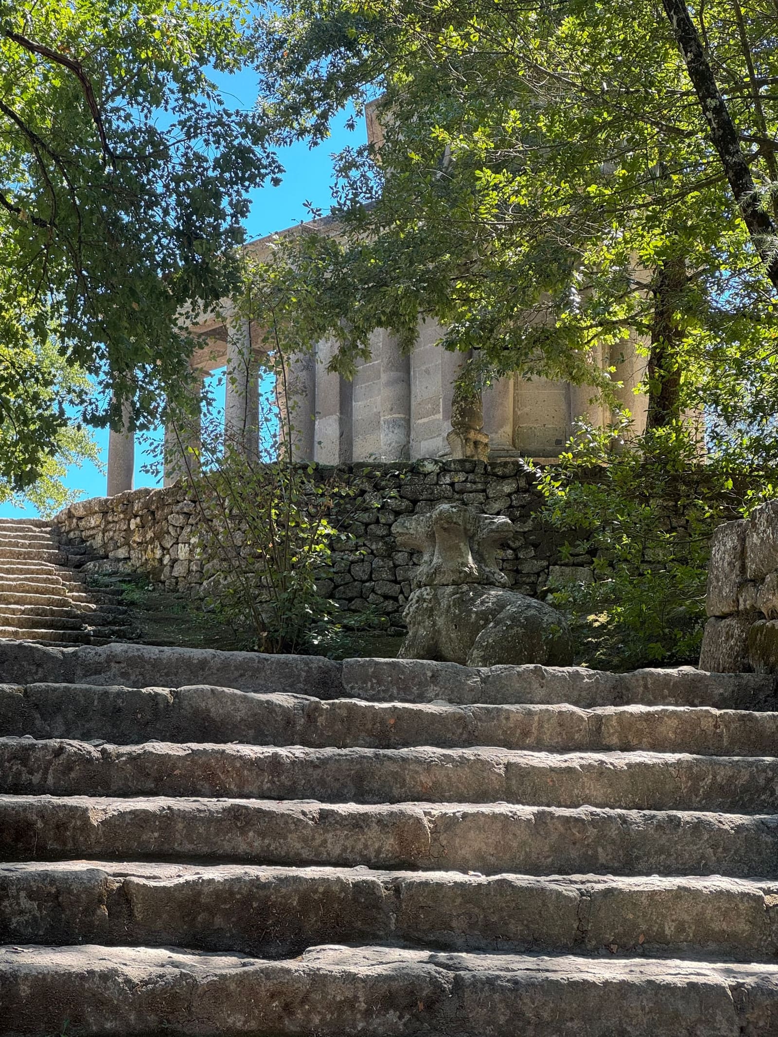 la scalinata di pietra che sale al tempietto, e il colonnato che si intravede fra le foglie