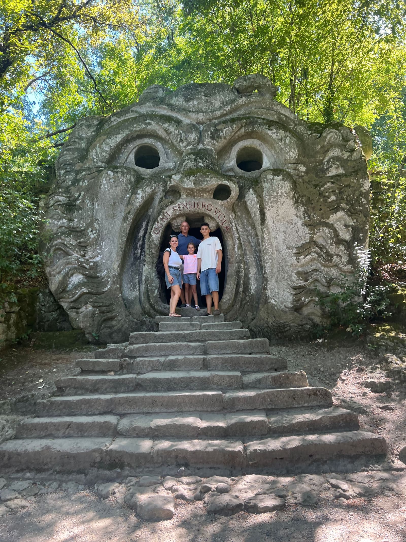 eccoci tutti e quattro in piedi dentro la bocca dell'orco, sopra la testa la scritta OGNI PENSIERO VOLA scavata nel labbro