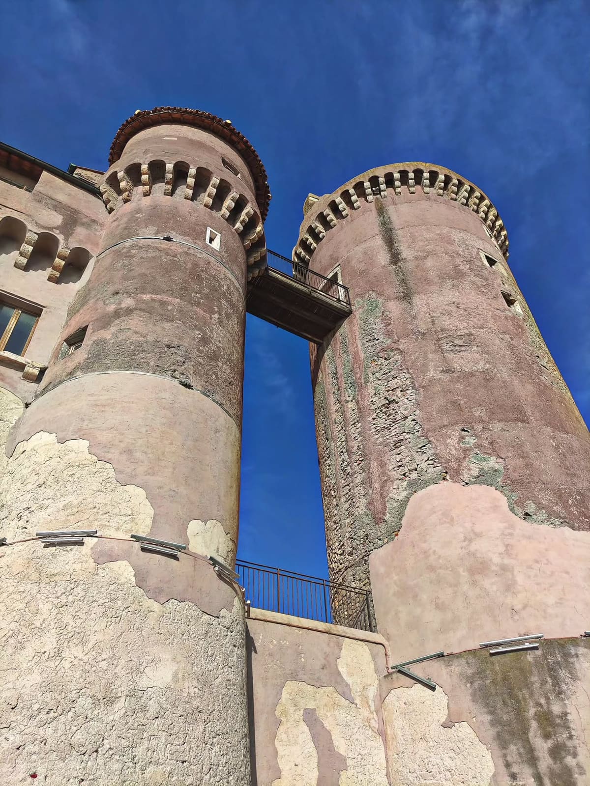 le due torri rotonde da sotto, unite in cima da una passerella di ferro: dove l'intonaco è caduto si legge la muratura di sassi che c'è sotto