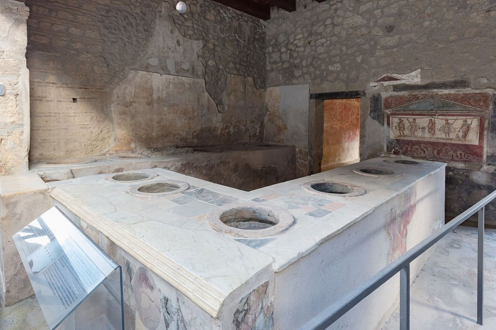 the counter with sunken jars of the thermopolium of Vetutius Placidus, and the painted lararium, in March