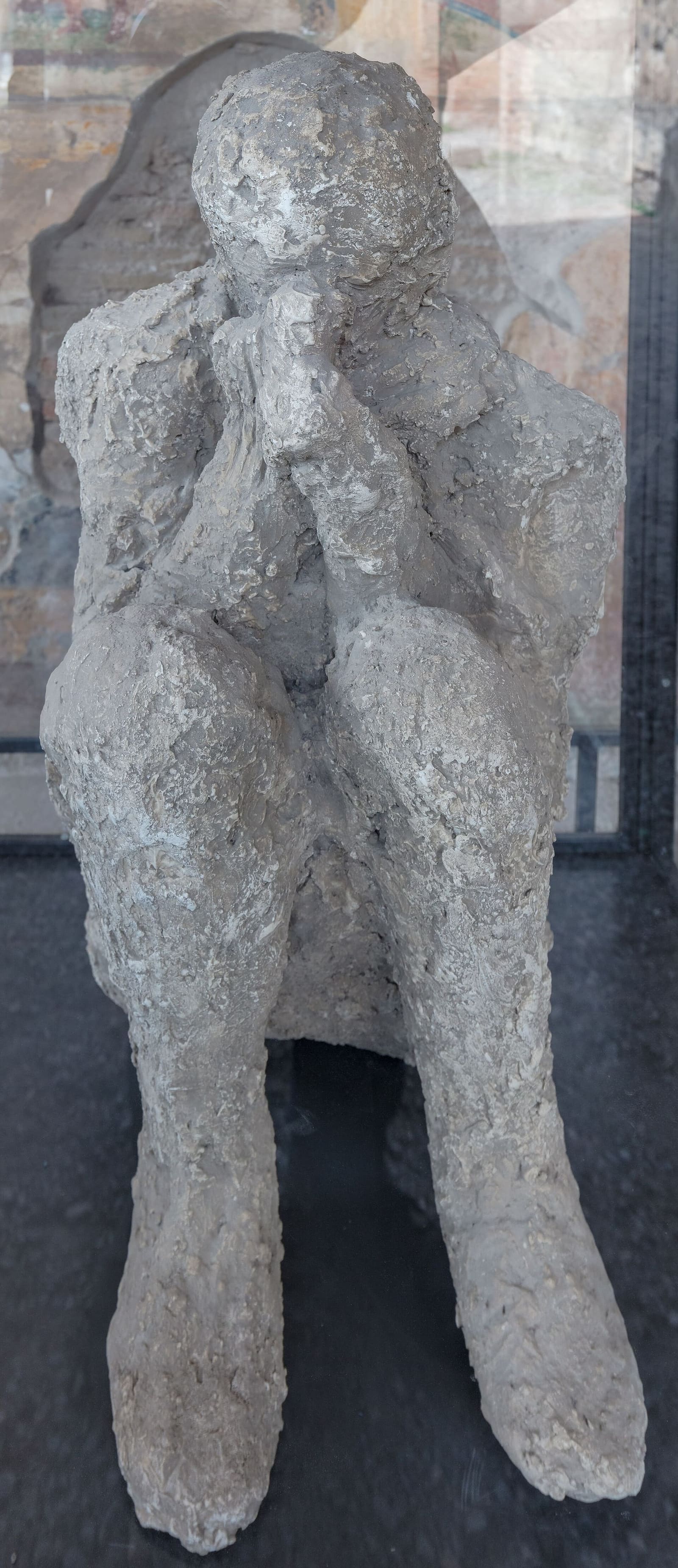 the cast of a seated man with his hands over his face, displayed in the Macellum in March 2023