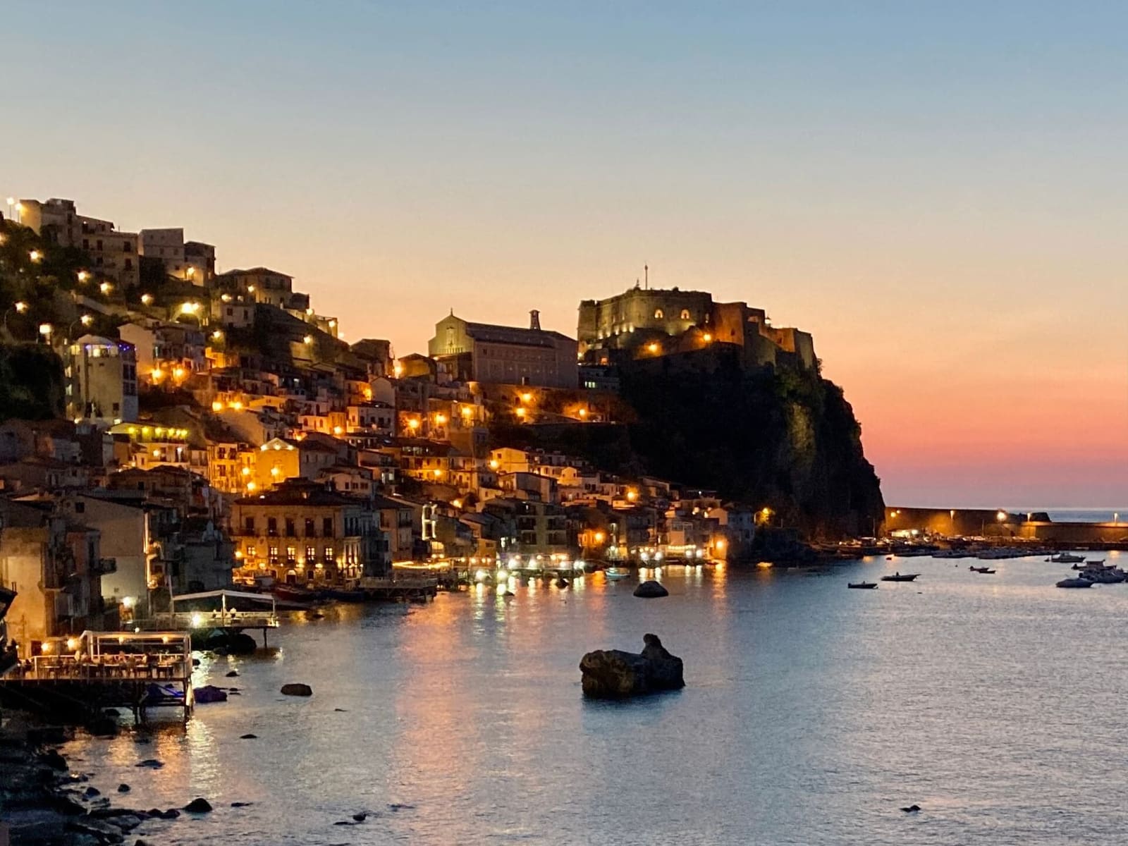 Chianalea lit up at sunset, with the castle rock