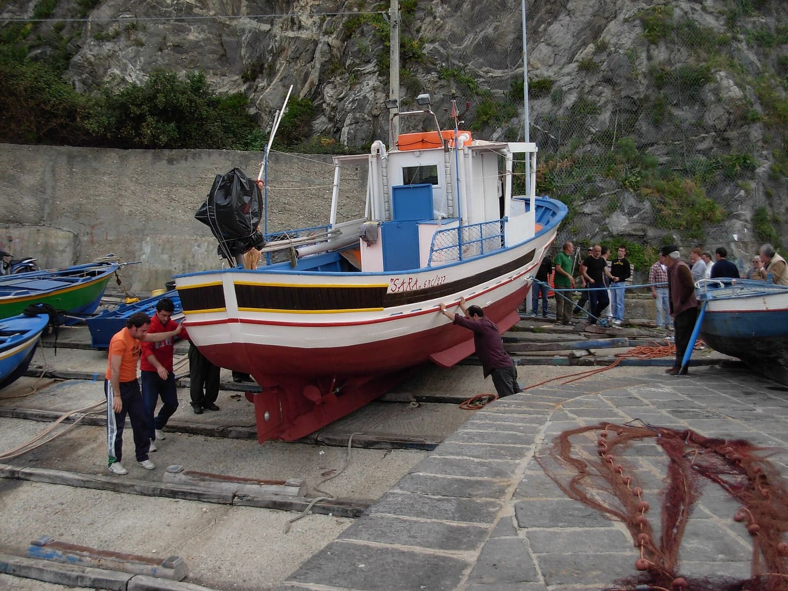 fishermen pushing a boat into the sea from the slipway below the castle