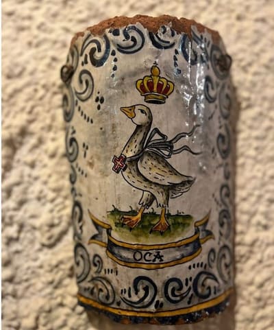 la targa in ceramica della Contrada dell'Oca, l'oca coronata dipinta a mano su un muro intonacato
