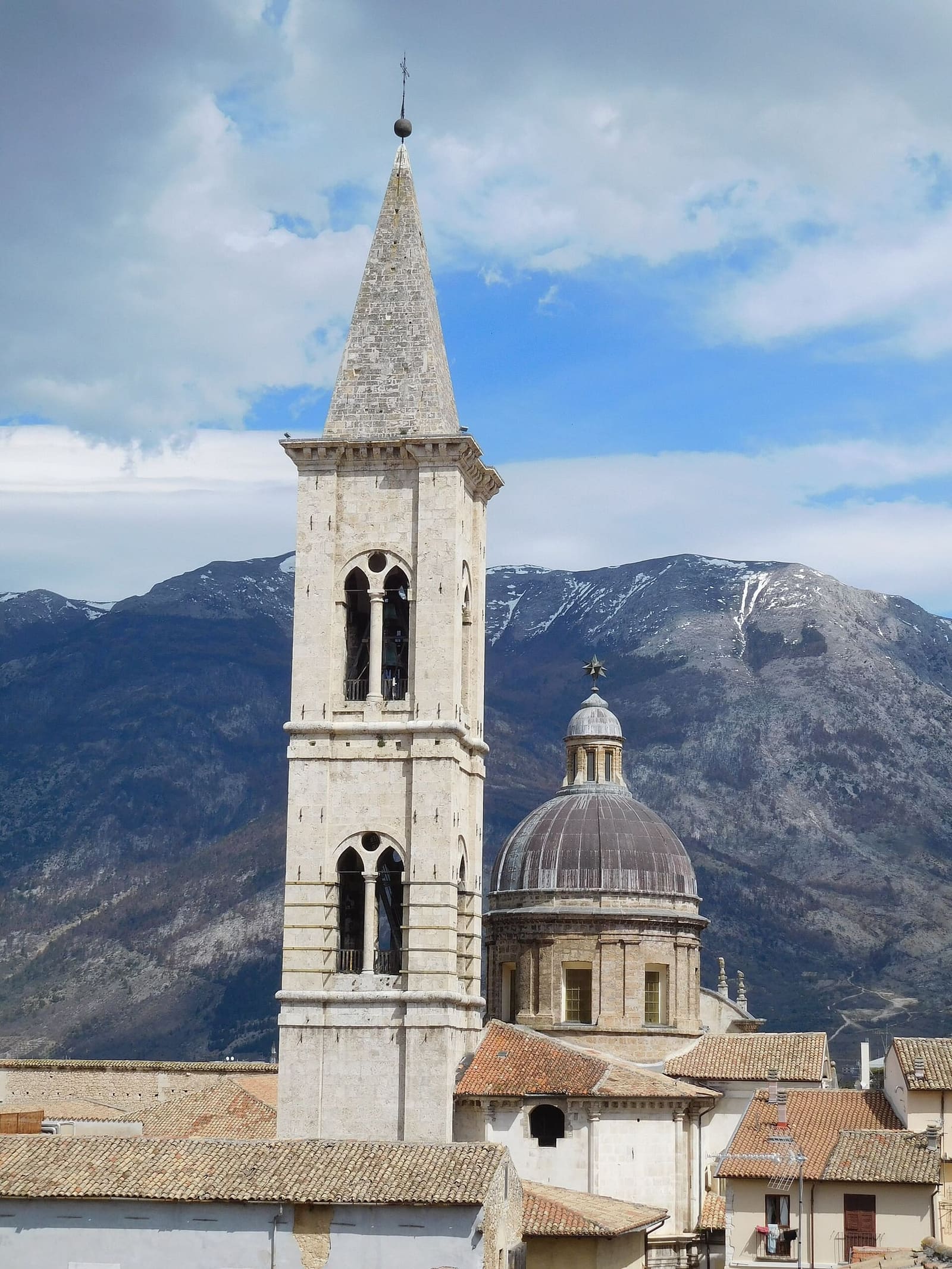 the bell tower and the dome of the Annunziata in front of the snow-capped mountains