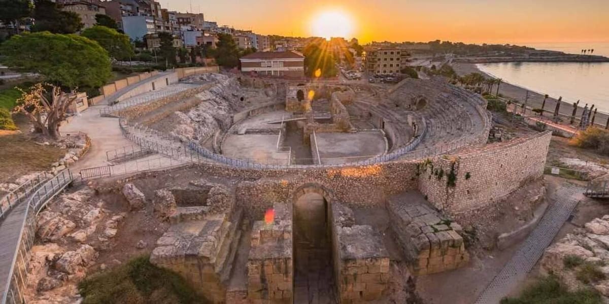 l'anfiteatro romano al tramonto, con la spiaggia e il mare alle spalle