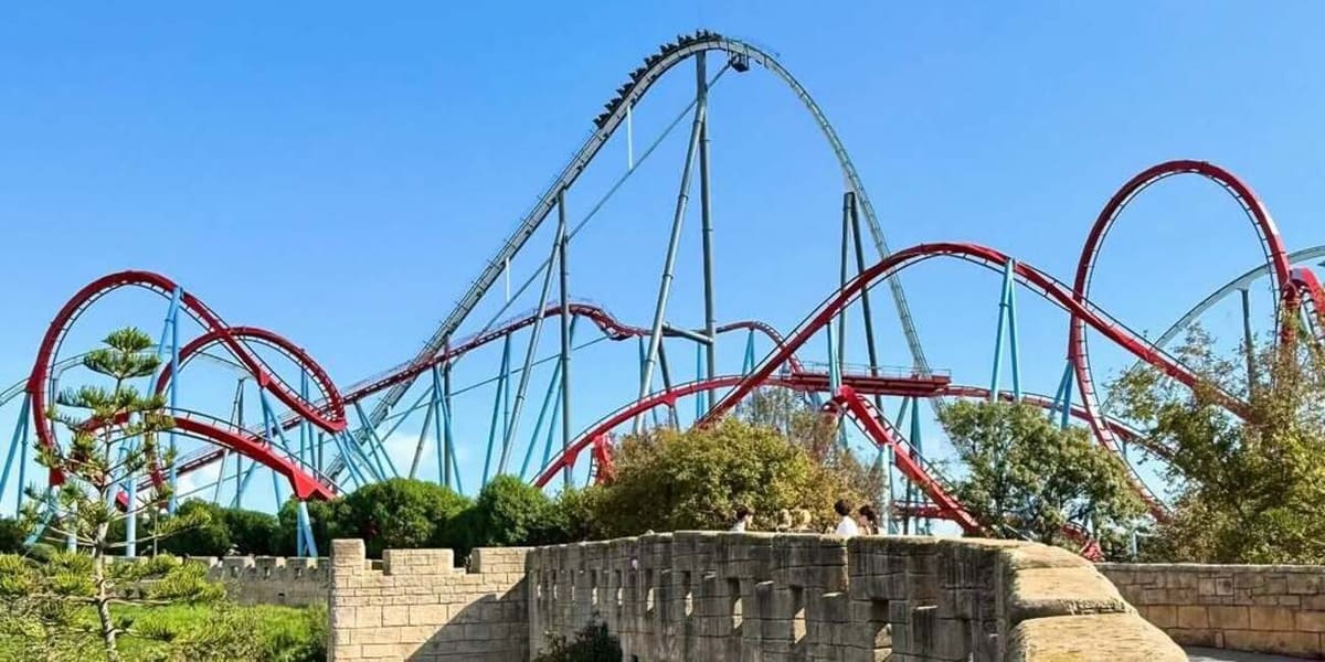le montagne russe rosse e azzurre di PortAventura sopra il muro di cinta di un'area tematica