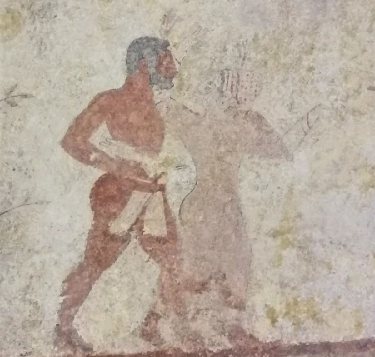 il ritratto di un uomo dalla barba grigia dipinto sulla parete, accanto a una figura più sbiadita