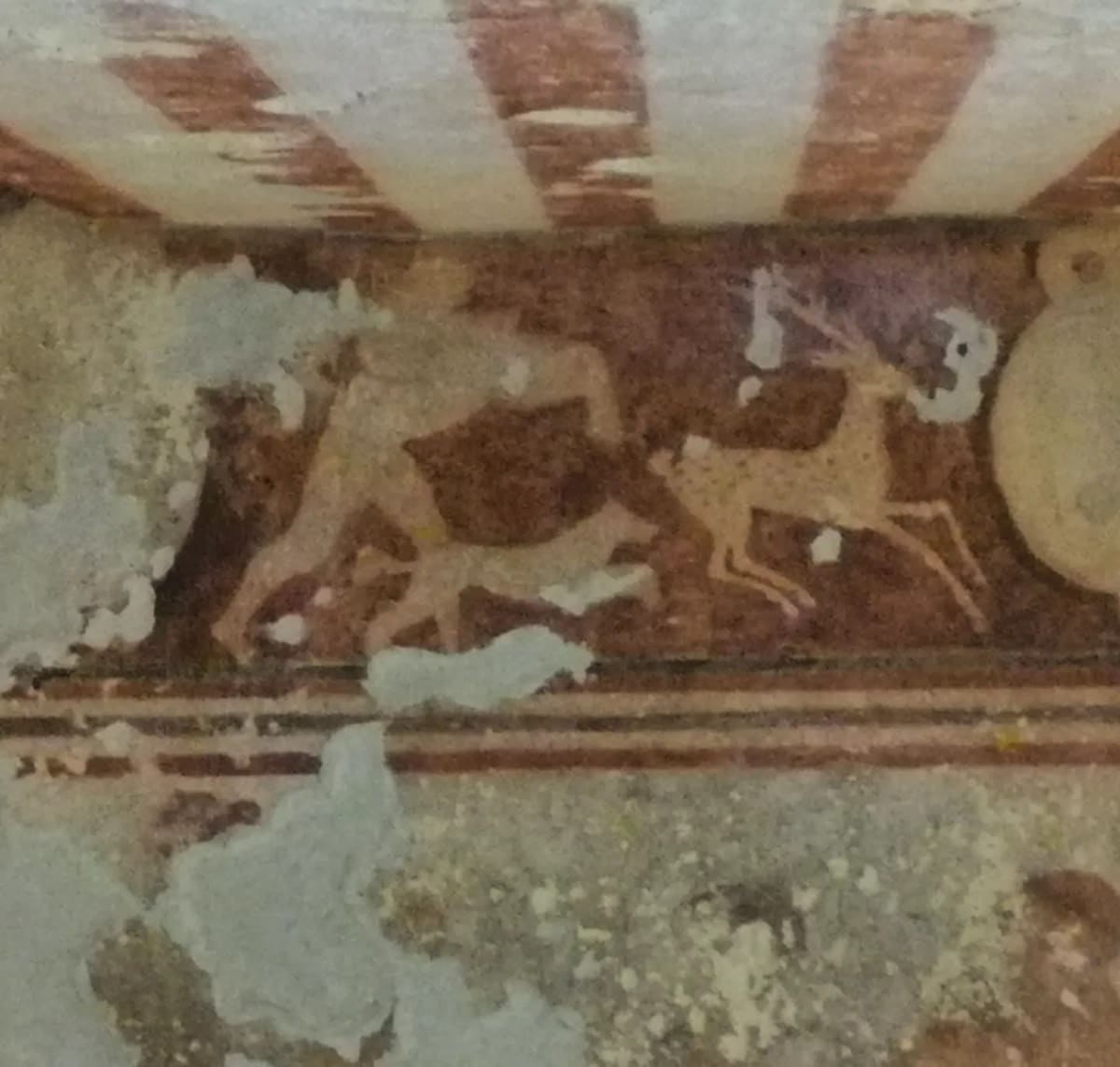 il fregio di una camera: una belva azzanna un cerbiatto sulla fascia rossa, sotto il soffitto a righe