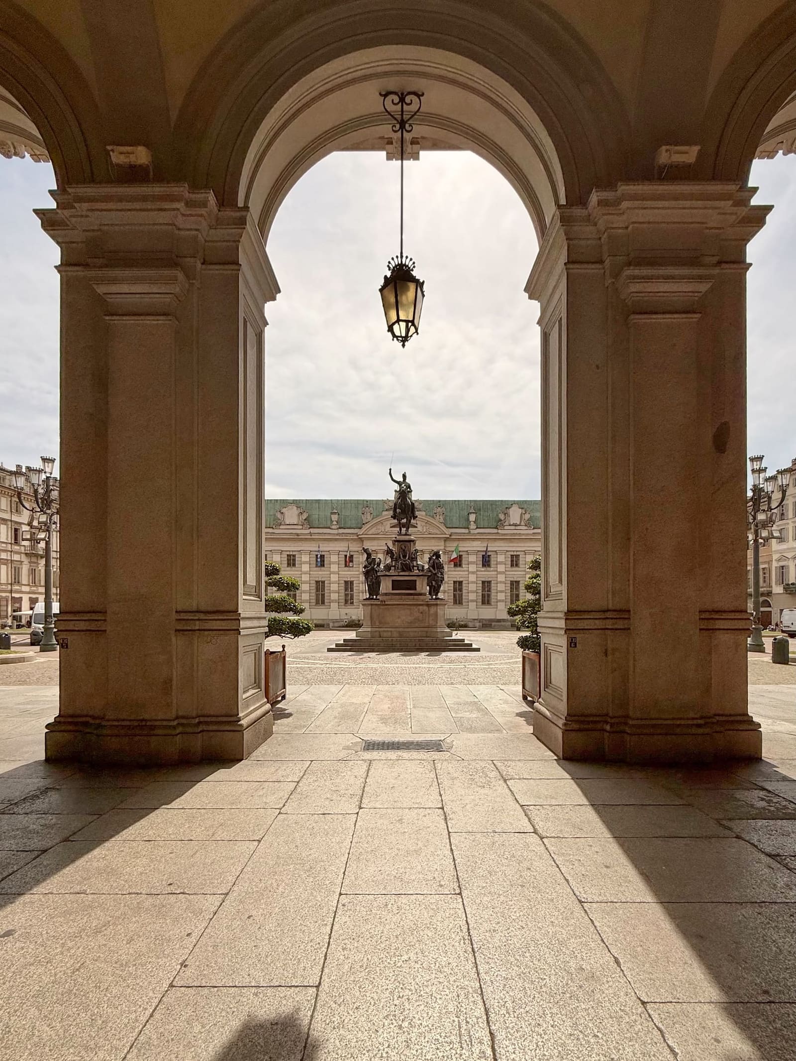 piazza Carlo Alberto incorniciata da un arco del portico, con il monumento equestre e la Biblioteca Nazionale dietro