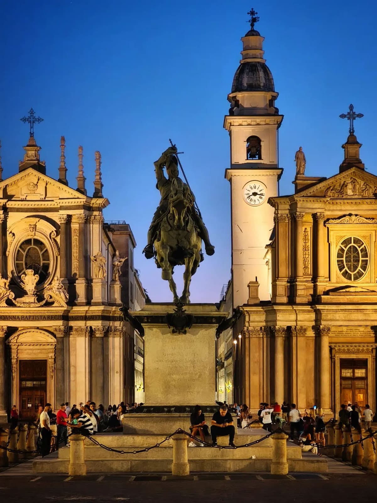 il Caval 'd Brons fra le facciate illuminate di San Carlo e Santa Cristina, all'ora in cui la piazza si riempie