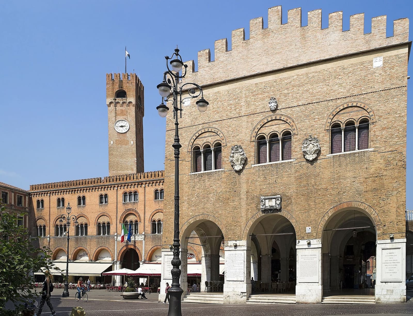 piazza dei Signori con il Palazzo dei Trecento, i portici e la torre civica, in una mattina di maggio