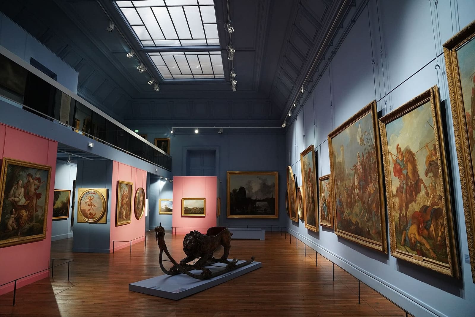 una sala dei dipinti del museo Saint-Loup, con le grandi tele antiche sulle pareti blu e rosa