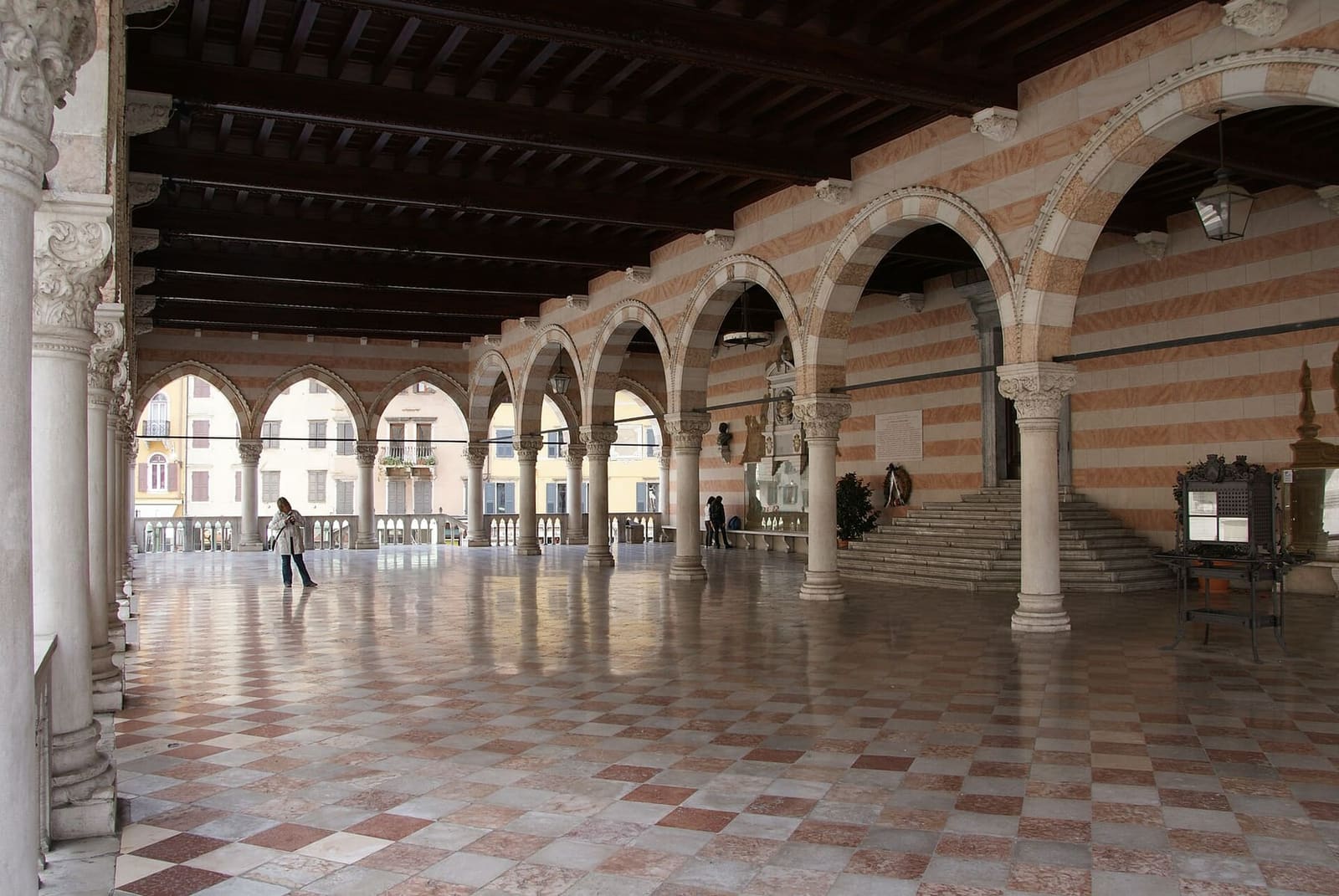 sotto le arcate della Loggia del Lionello, con il pavimento a scacchi e lo scalone