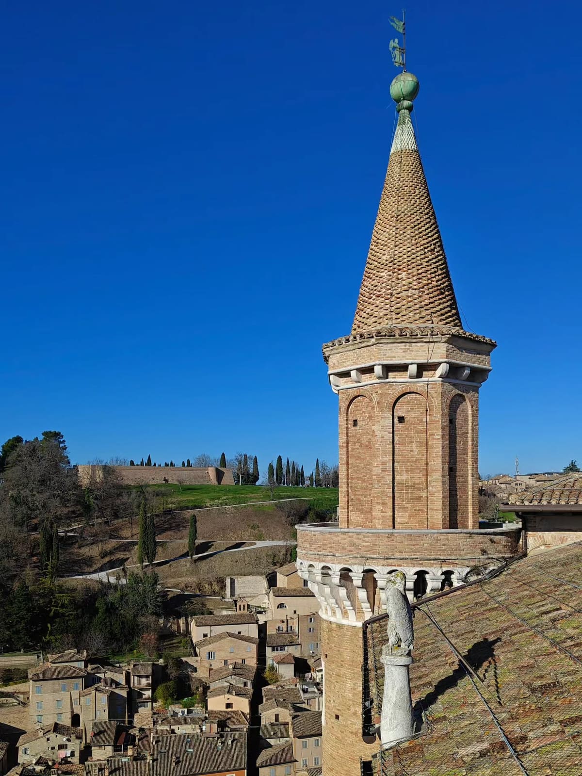 uno dei torricini da vicino, con il tetto di coppi a cono, e sulla collina di fronte la fortezza Albornoz