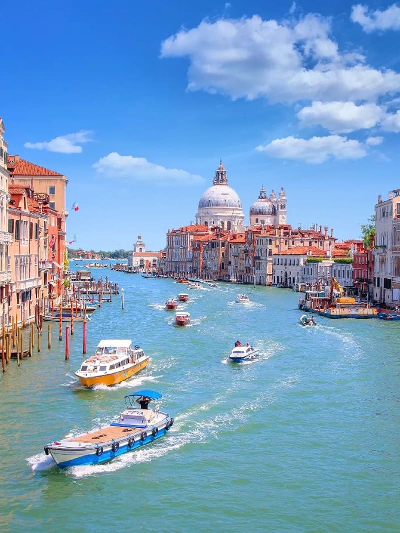 il Canal Grande in una giornata di sole, i taxi acquei in movimento e la cupola della Salute in fondo